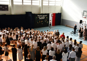 Społeczność szkolna śpiewa hymn narodowy.