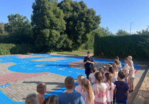 Pani policjantka omawia zasady przechodzenia przez przejście dla pieszych.