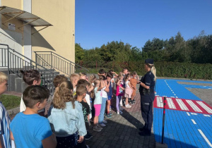 Pani policjantka omawia zasady bezpiecznego poruszania się w drodze do szkoły.