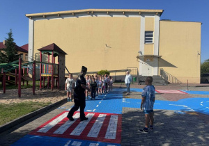Pani policjantka demonstruje prawidłowe przechodzenie przez przejście dla pieszych.
